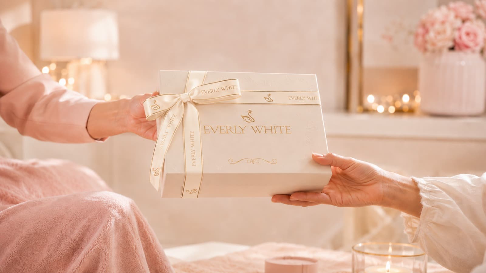 An Everly White gift box, tied with a signature ribbon, being handed from one person to another
